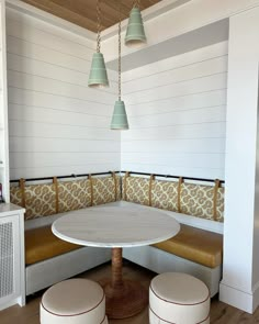 a white table sitting under three hanging lights next to two brown and white stools