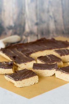 chocolate and peanut butter squares are arranged on top of a piece of brown parchment paper