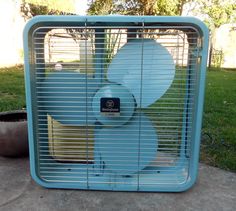 a blue fan sitting on top of a cement ground