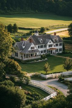 an aerial view of a large white house in the middle of a lush green field