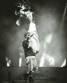 a man standing on top of a stage holding a baseball bat in his hand and looking at the crowd