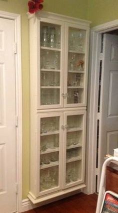 a white china cabinet with glass doors in a kitchen