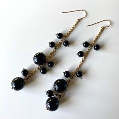 "Vintage black ball linear drop earrings. Gold tone (likely brass)  dangle drop earrings, with round black beads. The beads are made of glass (French jet).  Approximate measurements: 4\" drop. The largest ball bead is 12 mm. Condition: Very good condition with minimal wear - a tiny bit of tarnish to the gold tone metal on the end of the beads. Markings: None" Elegant Black Chandelier Earrings With Dangling Beads, Elegant Black Dangle Linear Earrings, Elegant Black Linear Dangle Earrings, Black Metal Earrings With Round Beads, Black Metal Round Beads Earrings, Black Dangle Linear Earrings, Black Chandelier Drop Earrings With Ear Wire, Black Dangle Linear Earrings For Pierced Ears, Black Long Drop Earrings With Dangling Beads