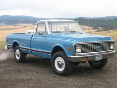 an old blue pickup truck is parked in the dirt