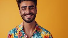 a man wearing a colorful shirt smiling at the camera with his hand on his hip