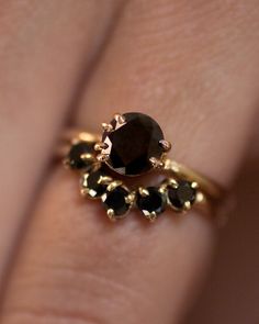 a woman's hand with a gold ring and black stones on her finger,