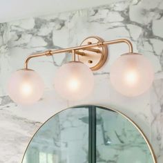 a bathroom with marble walls and three lights on the wall above the mirror, along with a round light fixture