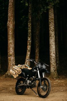 a dirt bike parked in the middle of a forest with logs on it's back