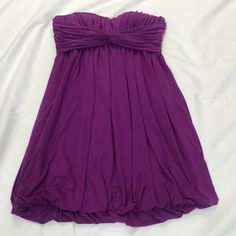 a purple dress laying on top of a white sheet