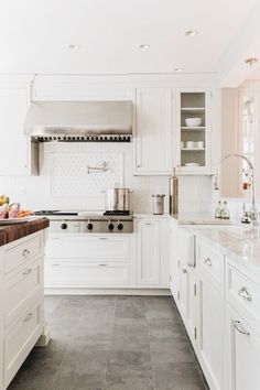 a large kitchen with white cabinets and marble counter tops, along with stainless steel appliances