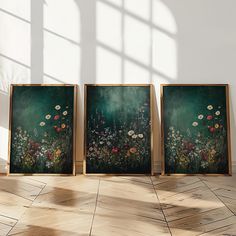 three framed paintings sitting on top of a wooden floor