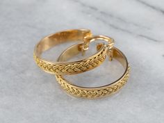 Absolutely gorgeous, these woven yellow gold hoop earrings catch the light in an excellent way! These are substantial in look but lightweight and easy to wear. The locking back closes securely, and the detailed braid design gives them marvelous dimension and texture. Metal: 14K Yellow Gold Earrings Length: 31 mm Earrings Width: 27 mm Marks: “14K” Stamped Yellow Gold Jewelry With Interwoven Design, Texture Metal, Braided Ring, Braid Designs, Yellow Gold Earrings, Yellow Gold Jewelry, Yellow Gold Earring, Gold Hoops, Jewelry Earrings Hoops