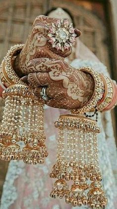 a woman in a bridal outfit holding some jewelry