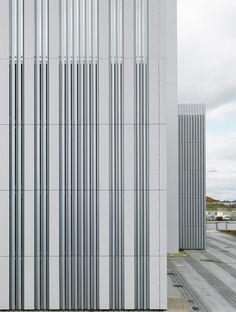 a tall white building with many vertical lines on it's side and the sky in the background