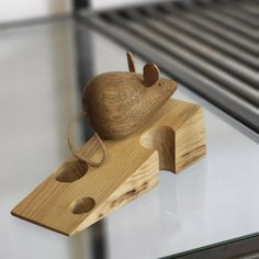 a wooden mouse sitting on top of a piece of wood next to a glass table