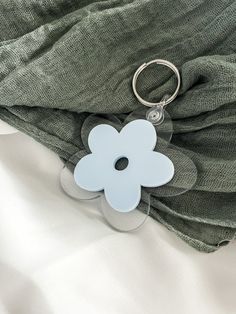 a white flower shaped keychain sitting on top of a bed