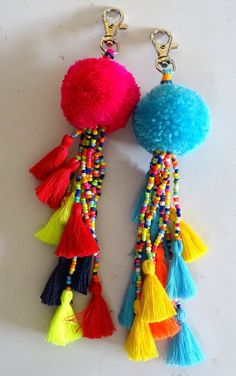 two tasselled pom - pom keychains on a white surface