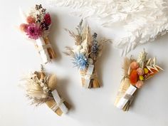 four different types of flowers are arranged on a white surface with feathers and branches in the background