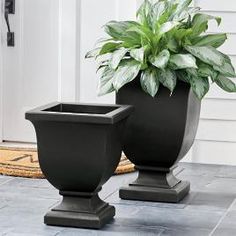 two black planters sitting on the ground next to each other in front of a door