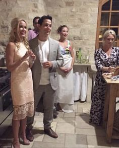 a group of people standing in a kitchen next to a table with food on it