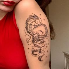 a woman's arm with a dragon tattoo on it and stars in the background