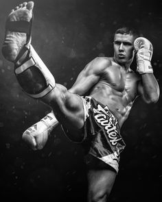 a black and white photo of a man kicking a kick with his leg in the air