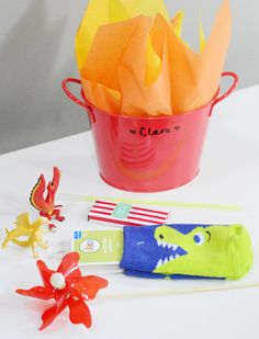 an assortment of toys and decorations on a white tablecloth with a red pail