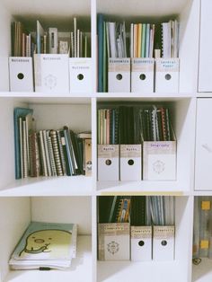 the books are lined up on the shelves in the room with white boxes and file folders