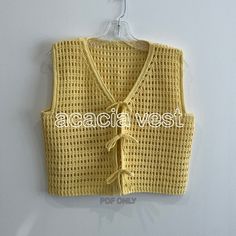 a yellow knitted vest hanging on a wall