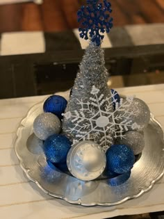 a silver plate topped with ornaments and a snowflake tree on top of it