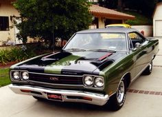 a green and black car parked in front of a house