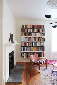 a living room filled with furniture and a fire place in front of a bookshelf