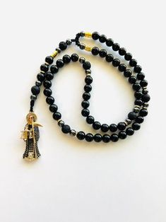 "Rosario hecho a mano de la Santa muerte Negra con piedras negra natural Obsidiana, piedra volcanica y piedras Hematite, rosario de piedras naturales proteccion de mas intensidad. Rosario ideal hecho para hombre o ideal para un regalo excepcional. Material utilizado: Dije de la Santa Muerte en oro laminado diamantado con cristales negro alrededor del cuerpo 2\" pulgadas Piedras negra natural Obsidiana 10mm Piedra negra Volcanica 10mm Piedra Hematite 8mm como espaciador Espaciador dorado de oro l Black Lava Stone Jewelry For Healing, Black Beads Cross Rosary Gift, Cheap Handmade Black Rosary, Santa Muerte Bracelet, Black Lava Stone Healing Jewelry, Adjustable Black Spiritual Rosary, Black Spiritual Lava Stone Jewelry, Black Lava Stone Spiritual Jewelry, Black Beaded Cross-shaped Rosary