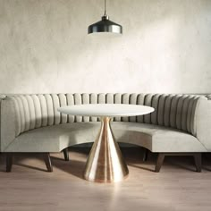 a round white table sitting on top of a wooden floor next to a beige couch