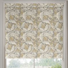 a window with an ornate roman blind in front of it and a potted plant next to the window