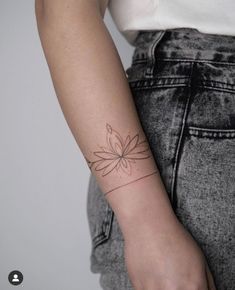 a woman's arm with a small flower tattoo on the left side of her arm