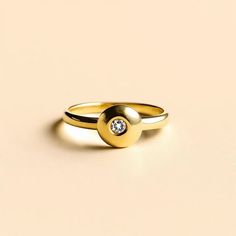 two gold rings with a single diamond on top of each one, sitting on a beige surface