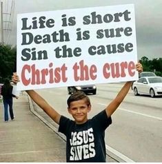 a young boy holding up a sign in spanish