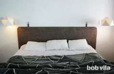 a bed with white pillows and black blanket on it's headboard in a bedroom