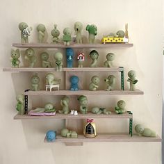 several shelves filled with small green figurines on top of each other in front of a white wall