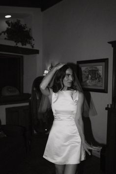 black and white photograph of a woman in a wedding dress holding her veil over her head