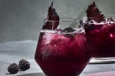 two glasses filled with liquid and some berries