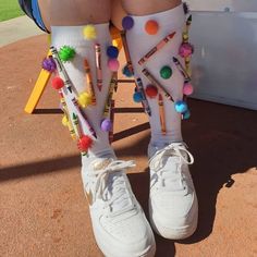 the legs of a person wearing white tennis shoes with colorful pom - poms on them