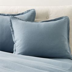 two blue pillows sitting on top of a bed