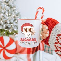 a person holding a coffee mug in front of a christmas tree with candy canes