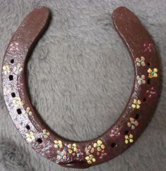 a close up of a brown horseshoe shaped object on a gray surface with flowers painted on it