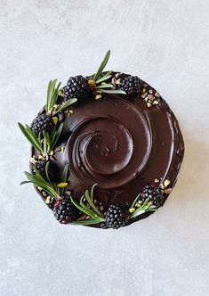 a chocolate cake topped with berries and rosemary