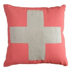 a red and white pillow with a cross on the front, in grey and pink