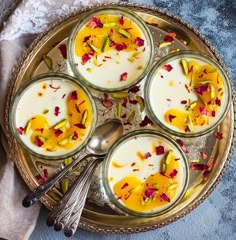 four desserts are sitting on a plate with spoons