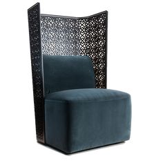 a chair that is sitting in front of a white wall with an intricate design on it